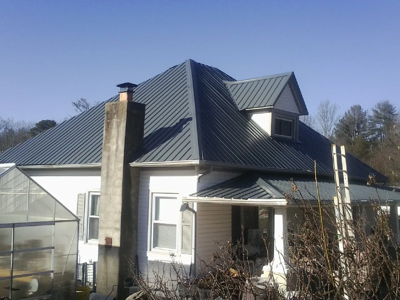 Dark blue standing seam metal roof on a white farmhouse with dormer — Slate & Tile Roof Repair by Roofing Brothers in La Jose