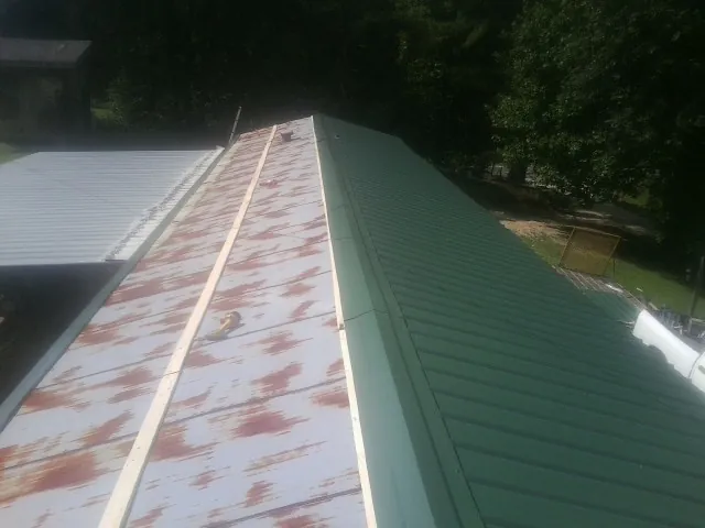 Old rusted panels beside newly installed green metal roofing — Wind Damage Roof Repair by Roofing Brothers in La Jose