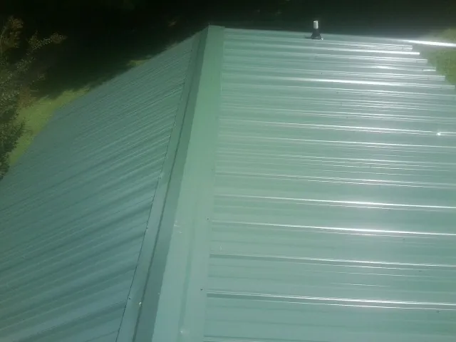 New green metal panels meeting at the ridge of a roof — Flat Roof Repair work by our crew in La Jose