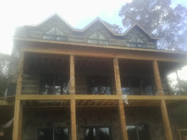 Dormers and porch framing on a large log home under construction — Roof Coating work by our crew in La Jose
