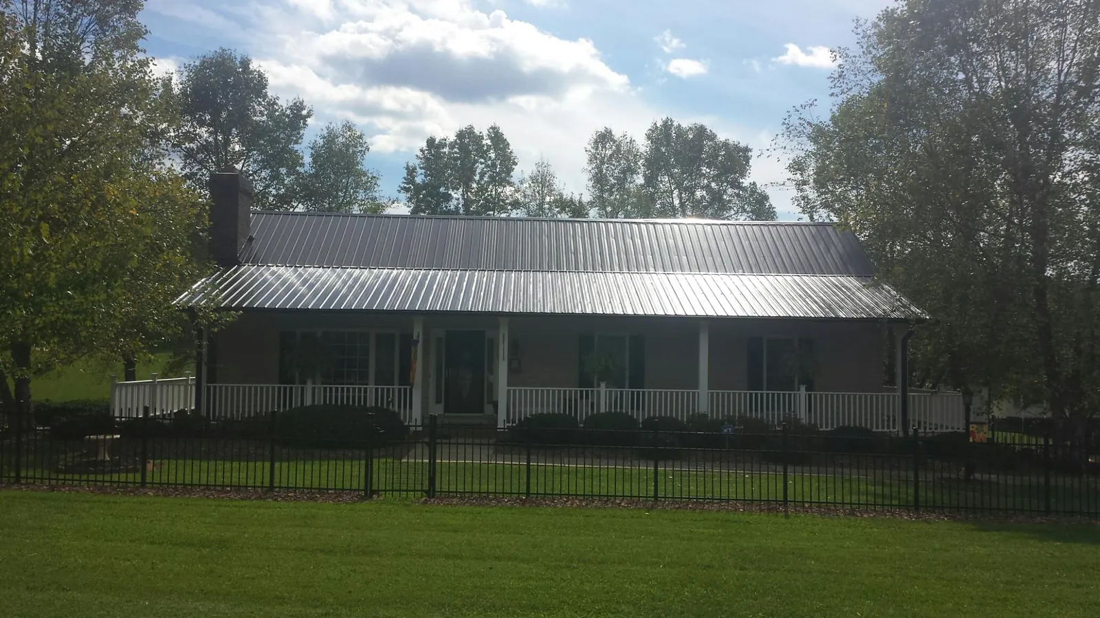 Gray metal roof on a brick ranch with a full width front porch — Gutter Guard Installation work by our crew in La Jose