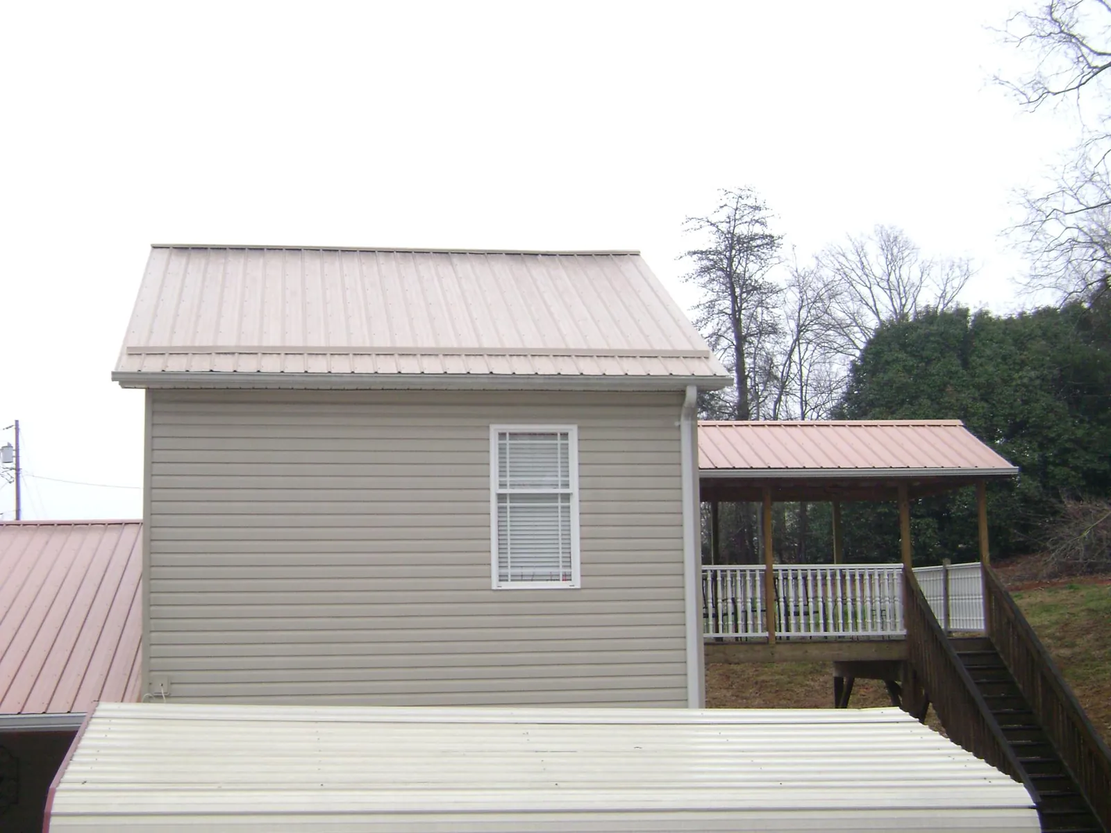 Tan metal roofs on a two story addition and attached porch, from a Roof Replacement job in La Jose